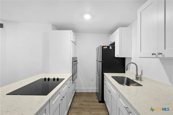 a kitchen with a sink a refrigerator and cabinets