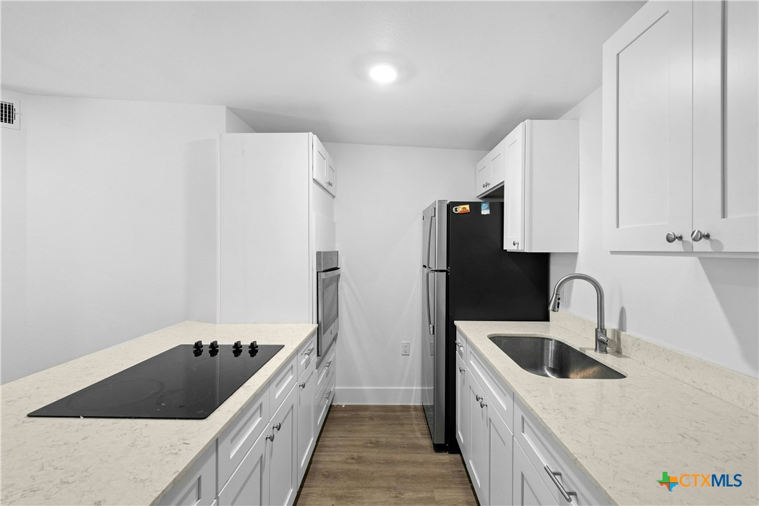 1007 Hackberry Street San Marcos, TX 78666 - Photo 19 of 36 a kitchen with a sink a refrigerator and cabinets