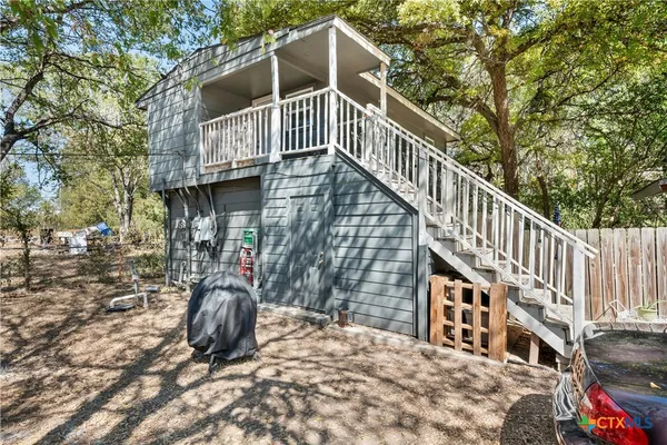 a view of a house with large trees and wooden fence