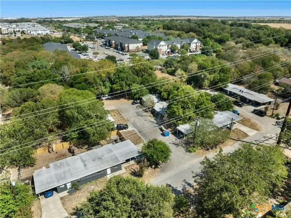 an aerial view of residential houses with outdoor space and trees