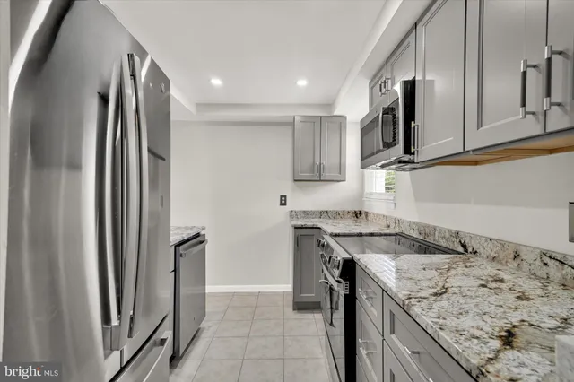 a kitchen with stainless steel appliances granite countertop a refrigerator a stove and a sink