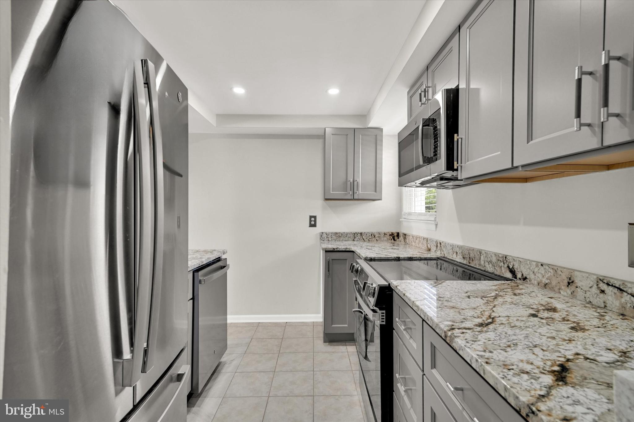 a kitchen with stainless steel appliances granite countertop a refrigerator a stove and a sink