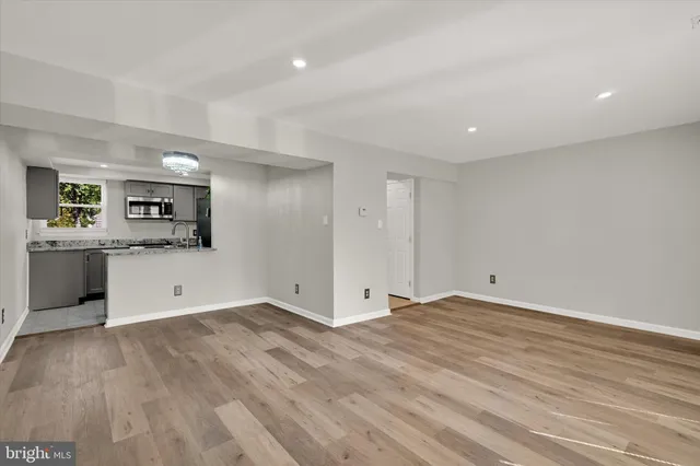 a view of an empty room with window and wooden floor