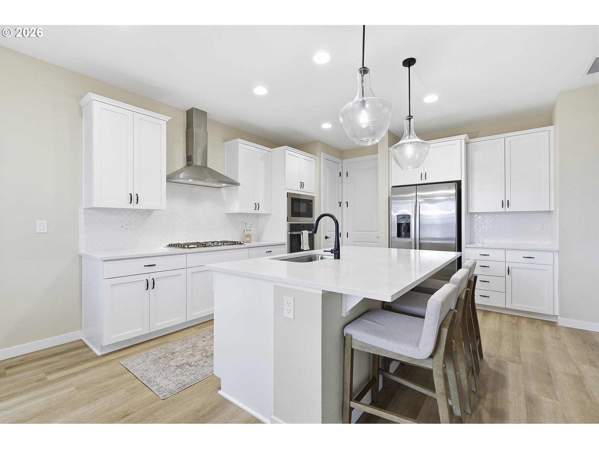 6724 Southwest Lupine Way Wilsonville, OR 97070 - Photo 16 of 45 a kitchen with stainless steel appliances kitchen island granite countertop a sink a stove a refrigerator and white cabinets with wooden floor