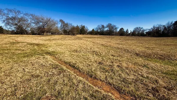 a view of a field with an ocean in background