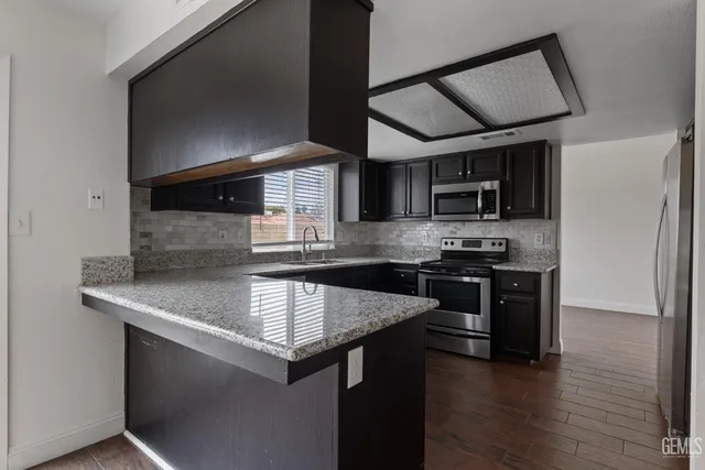 a kitchen with stainless steel appliances granite countertop a sink stove and microwave