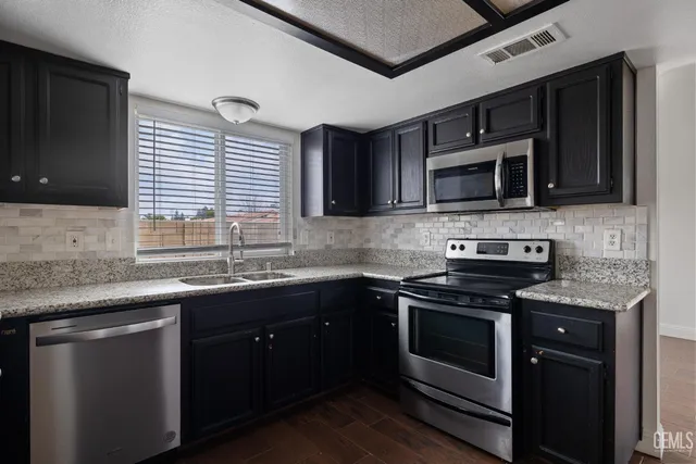 a kitchen with stainless steel appliances a stove sink microwave and cabinets