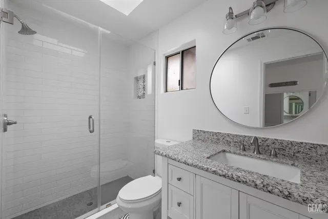 a bathroom with a granite countertop toilet a sink and mirror