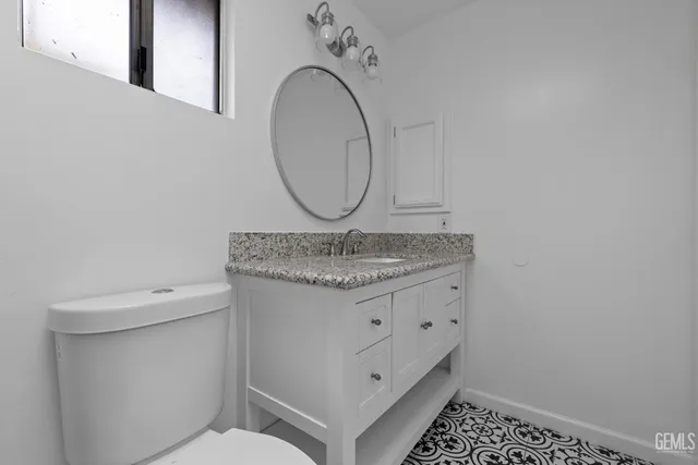 a bathroom with a granite countertop sink a mirror and a toilet