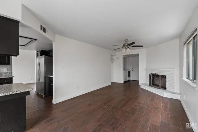 an empty room with wooden floor fireplace and windows