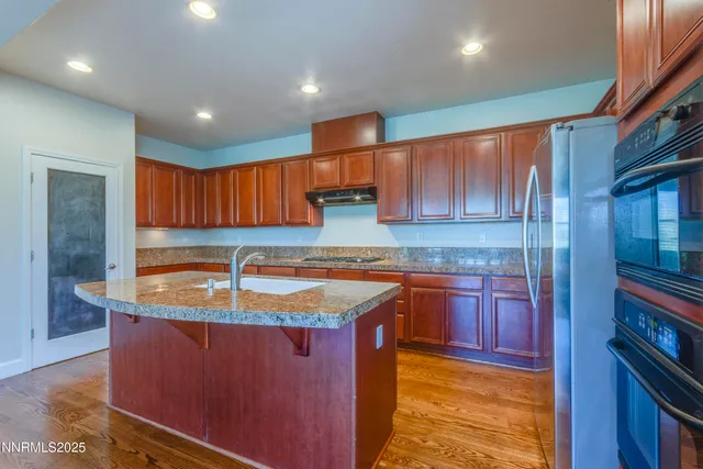 a kitchen with kitchen island granite countertop a sink and wooden cabinets