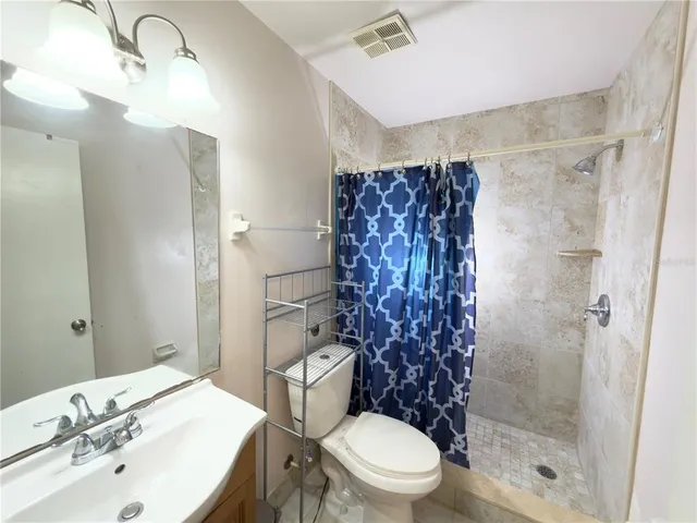 an empty room with a chandelier fan and windows