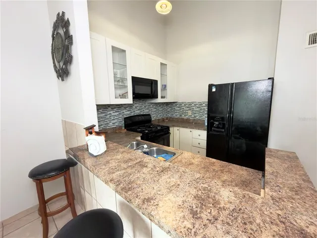 a kitchen with stainless steel appliances kitchen island granite countertop a refrigerator a stove a sink a microwave and with a dining table