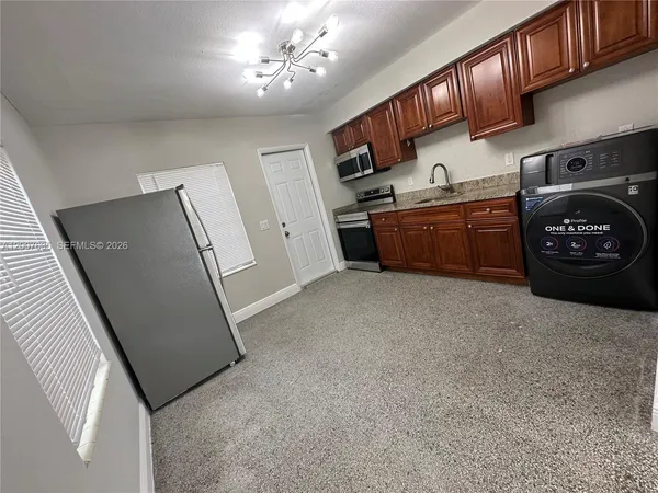 a kitchen with stainless steel appliances granite countertop a refrigerator a sink dishwasher a stove and a dining table with wooden floor