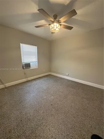 an empty room with a chandelier fan and windows