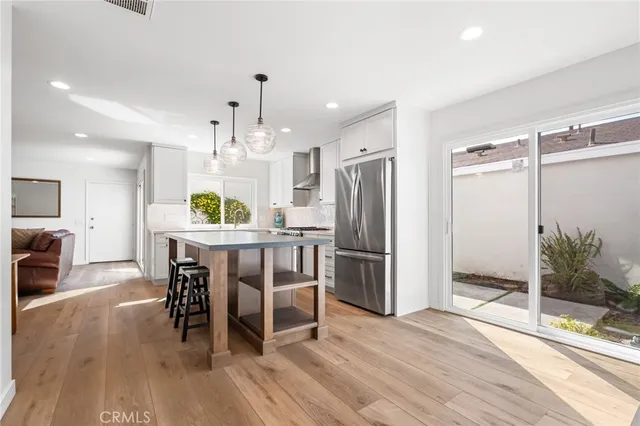 a kitchen with stainless steel appliances a dining table chairs stove and refrigerator