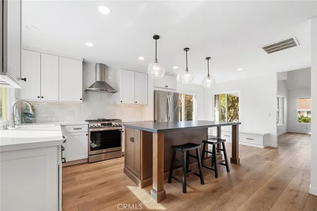 a kitchen with stainless steel appliances granite countertop a stove top oven a refrigerator a sink and a dining table with wooden floor