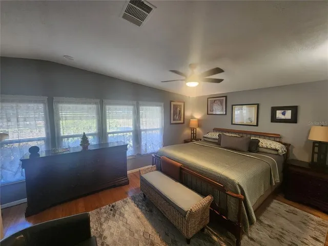 a spacious bedroom with a bed and wooden floor