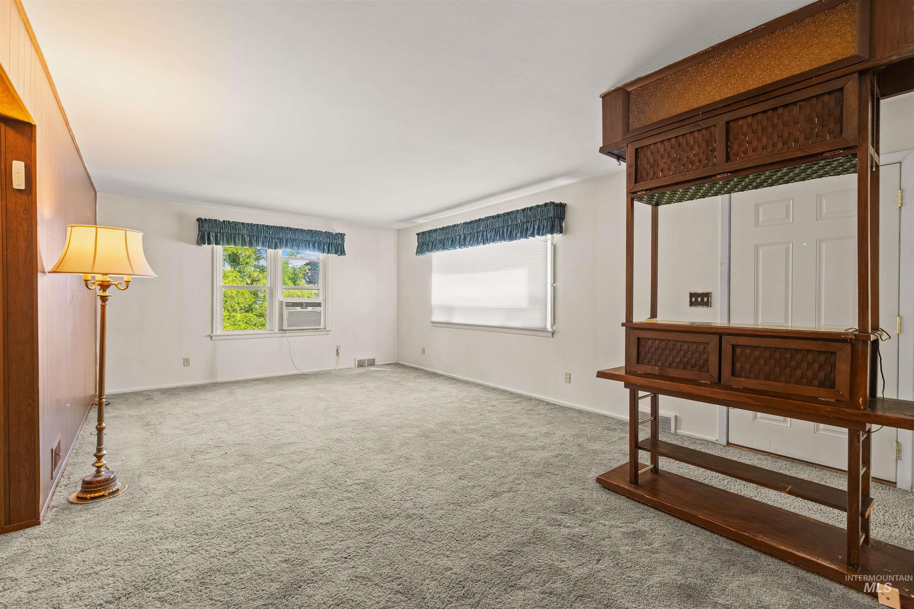 1663 9th Avenue Lewiston, ID 83501 - Photo 9 of 36 Spacious carpeted room featuring multiple windows, white walls, and a built-in wooden shelving unit with a mirrored back