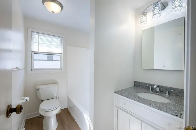 a bathroom with a granite countertop toilet a sink and mirror