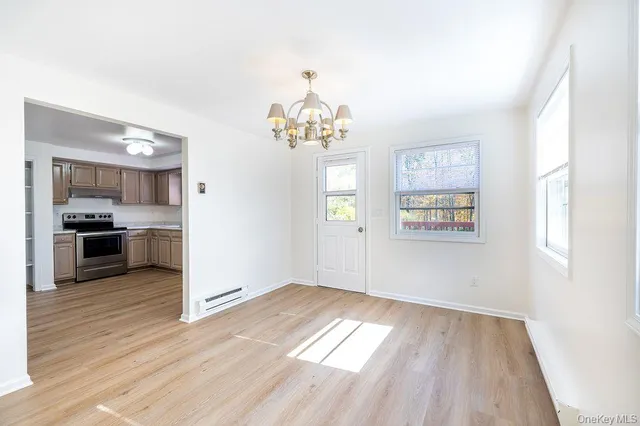 a view of a kitchen and an empty room with wooden floor