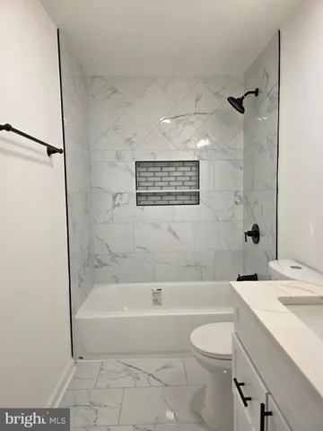 a bathroom with a granite countertop bathtub shower sink vanity and toilet