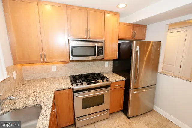 a kitchen with stainless steel appliances granite countertop a refrigerator stove and microwave