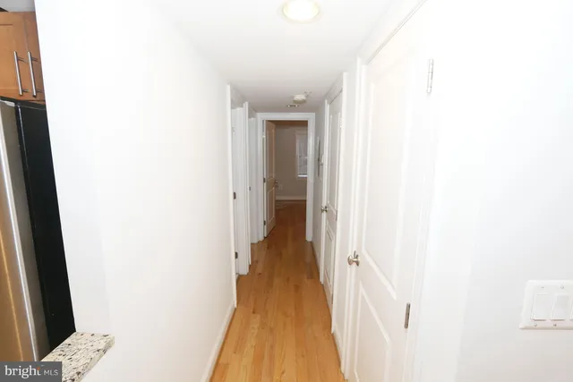 a view of a hallway with wooden floor and a bathroom