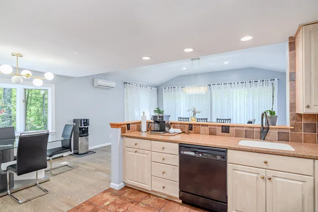 a kitchen with a sink dishwasher a dining table and chairs with wooden floor