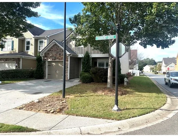 a view of a white house with large tree next to a road