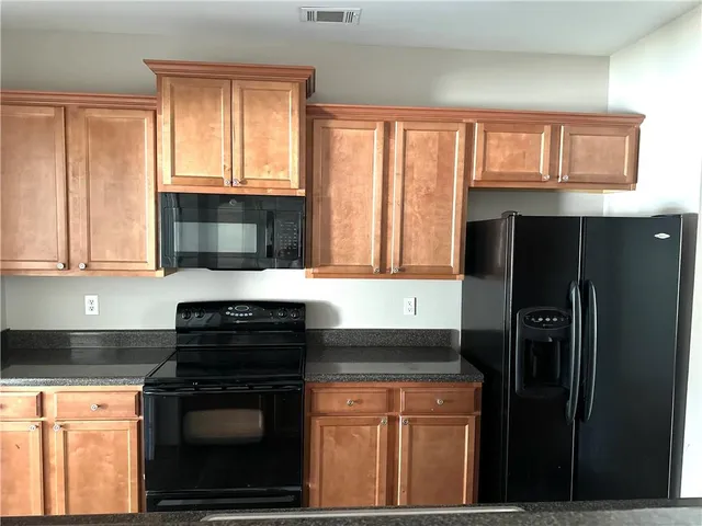 a kitchen with granite countertop a refrigerator stove and microwave