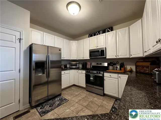 a kitchen with granite countertop a refrigerator and a stove top oven