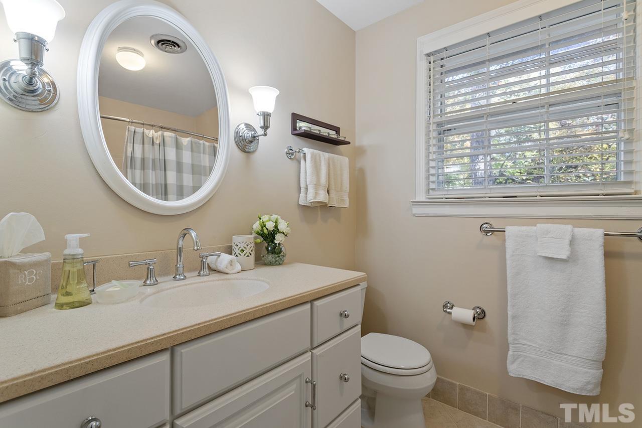 2408 Wentworth Street Raleigh, NC 27612 - Photo 28 of 33 a bathroom with a toilet a sink a mirror and a window
