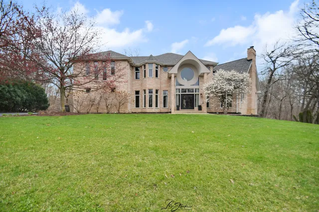 a view of a white house with a big yard and large trees