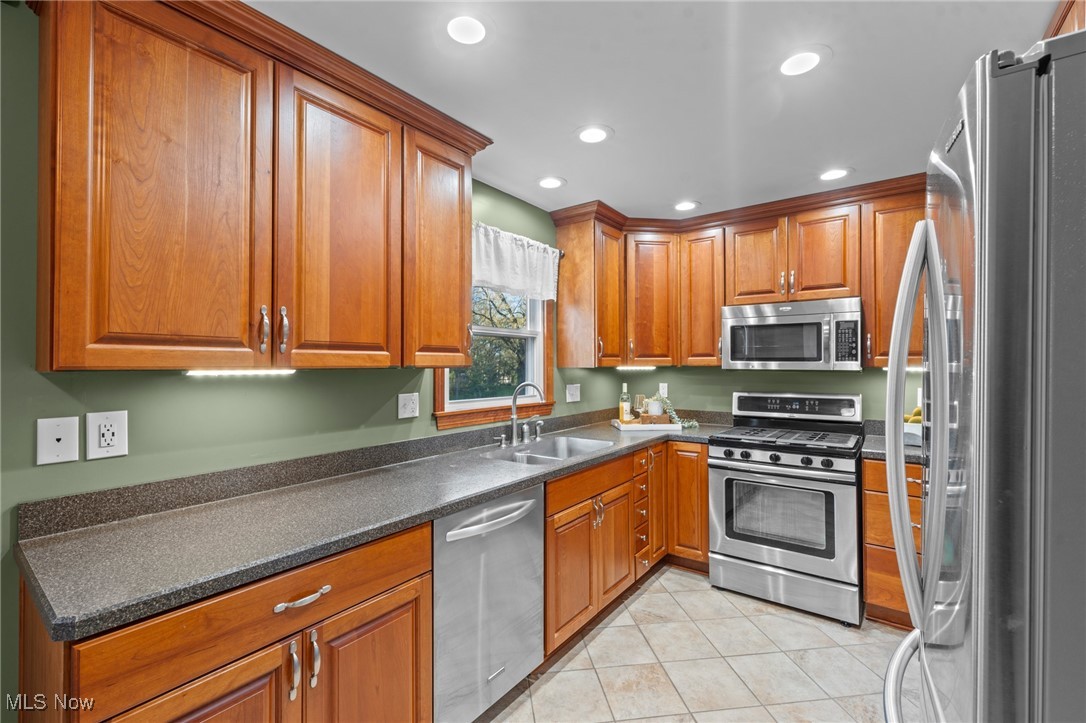 6315 Brookside Road Independence, OH 44131 - Photo 11 of 41 Kitchen with dark countertops, appliances with stainless steel finishes, a sink, brown cabinetry, and light tile patterned floors