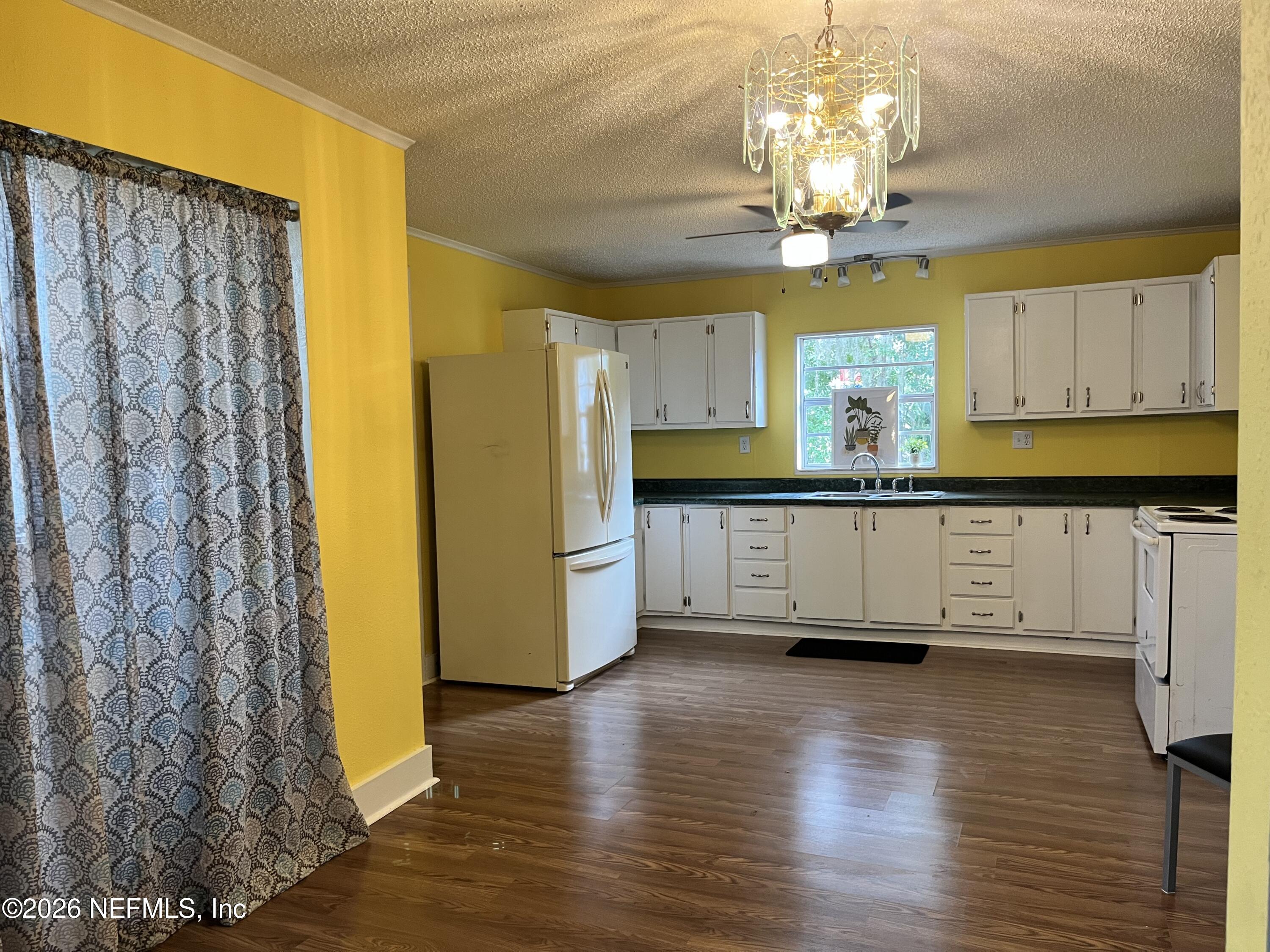 624 North Lake Street Starke, FL 32091 - Photo 19 of 34 a kitchen with granite countertop white cabinets and chandelier