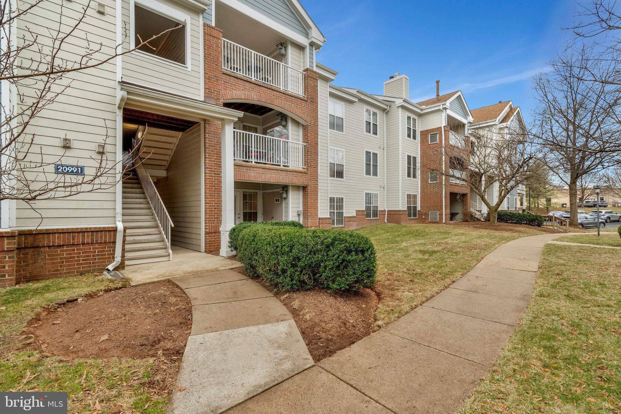 20991 Timber Ridge Terrace, Unit 103 Ashburn, VA 20147 - Photo 1 of 58 a front view of a building with a yard