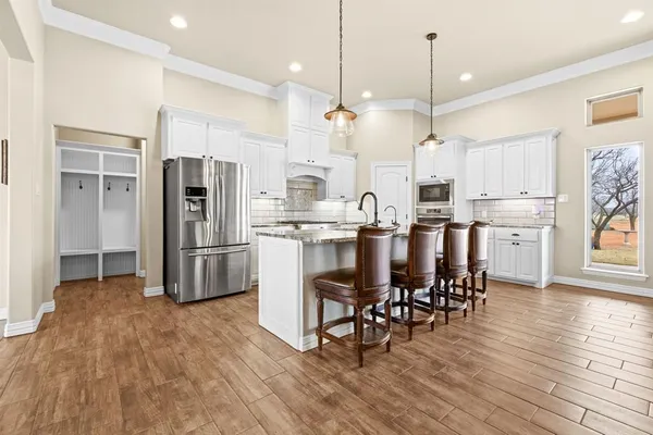 a kitchen with stainless steel appliances a dining table chairs refrigerator and microwave