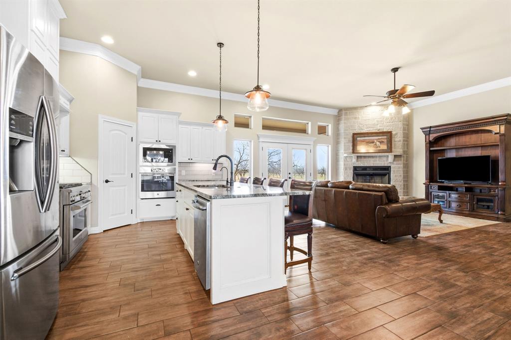 146 Mesquite Ridge Lane Lawn, TX 79530 - Photo 39 of 40 a kitchen with stainless steel appliances kitchen island granite countertop a stove top oven a sink a dining table and chairs with wooden floor
