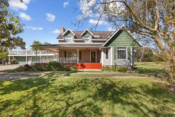 a view of a house with a big yard plants and large tree