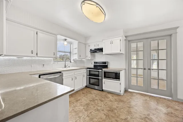 a kitchen with granite countertop a stove a sink and a refrigerator