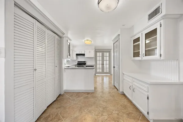 a view of kitchen with refrigerator and white cabinets