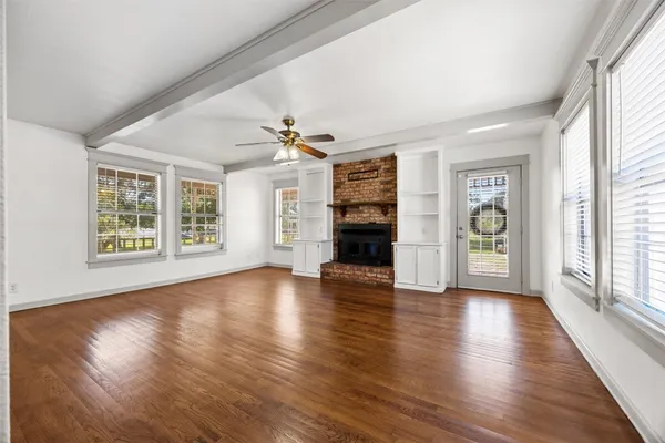 an empty room with wooden floor chandelier and windows