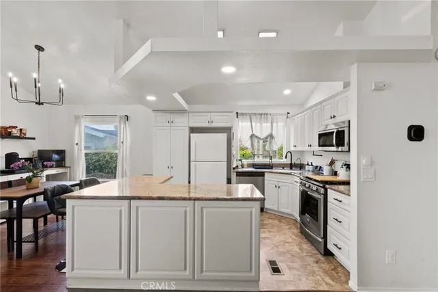 a kitchen with stainless steel appliances kitchen island granite countertop a stove top oven a sink a dining table and chairs