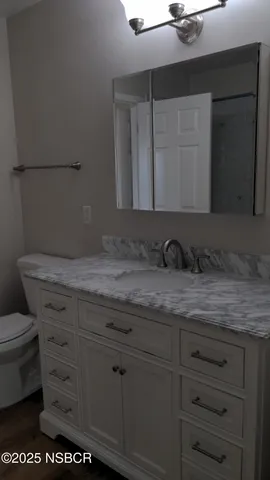 a bathroom with a granite countertop sink vanity mirror and toilet