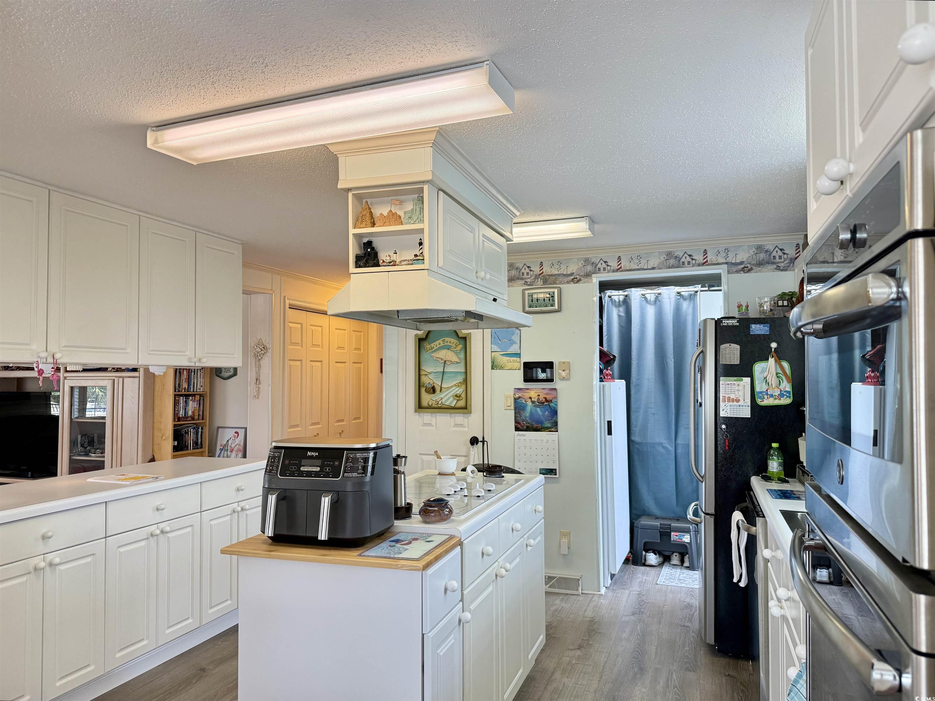 1506 Mason Circle Surfside Beach, SC 29575 - Photo 2 of 33 Kitchen featuring white cabinetry, light wood-style floors, a textured ceiling, white cooktop, and light countertops