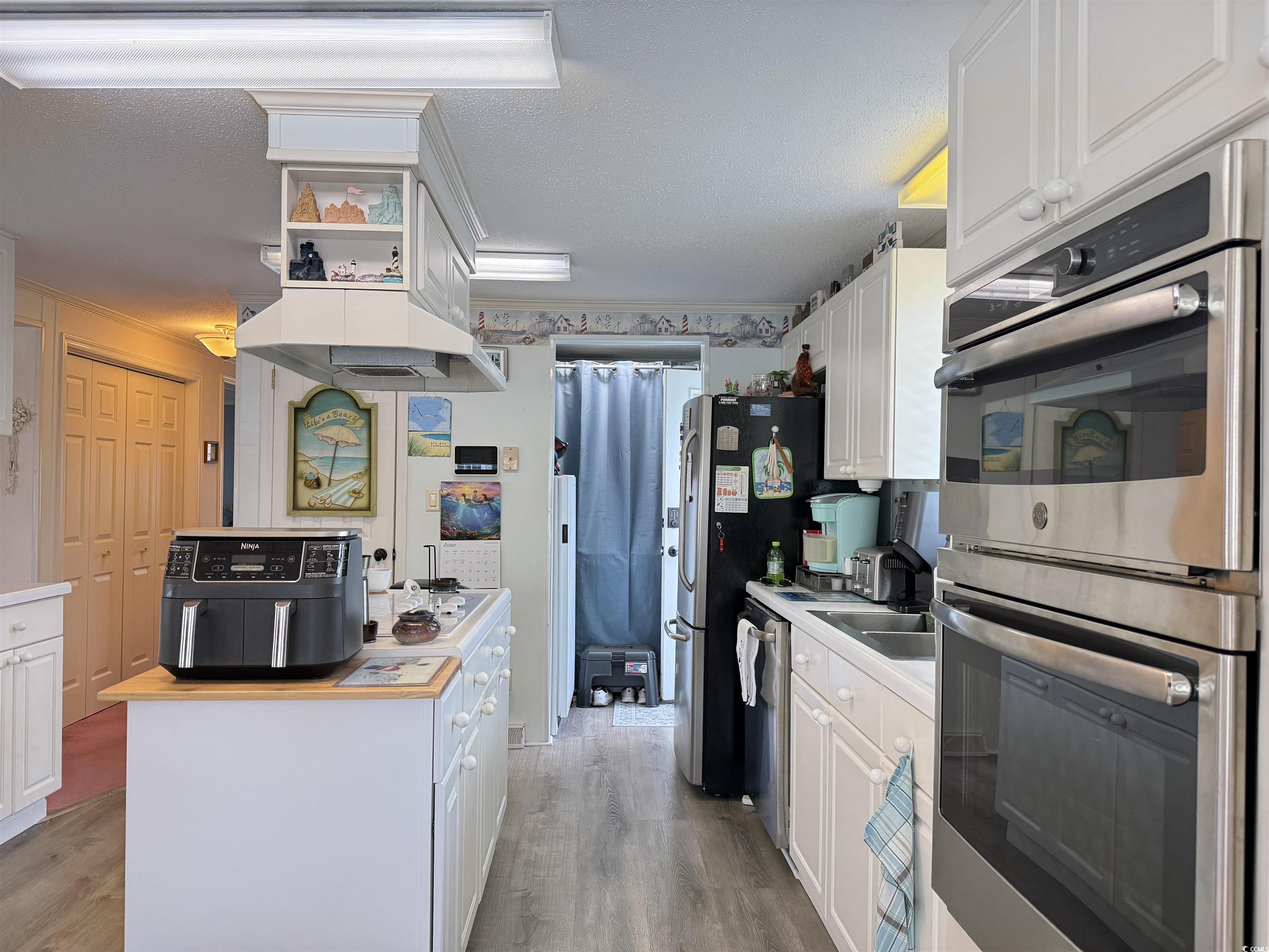 1506 Mason Circle Surfside Beach, SC 29575 - Photo 3 of 33 Kitchen with appliances with stainless steel finishes, light wood finished floors, white cabinetry, and ornamental molding