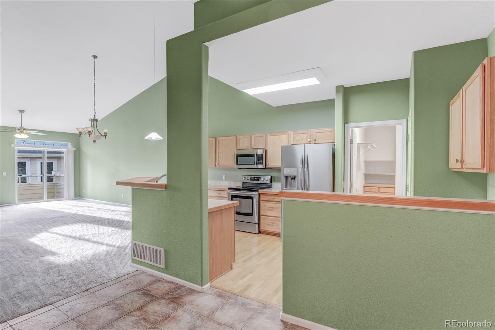 6656 South Reed Way, Unit B Littleton, CO 80123 - Photo 3 of 32 a kitchen with kitchen island a sink stainless steel appliances and cabinets