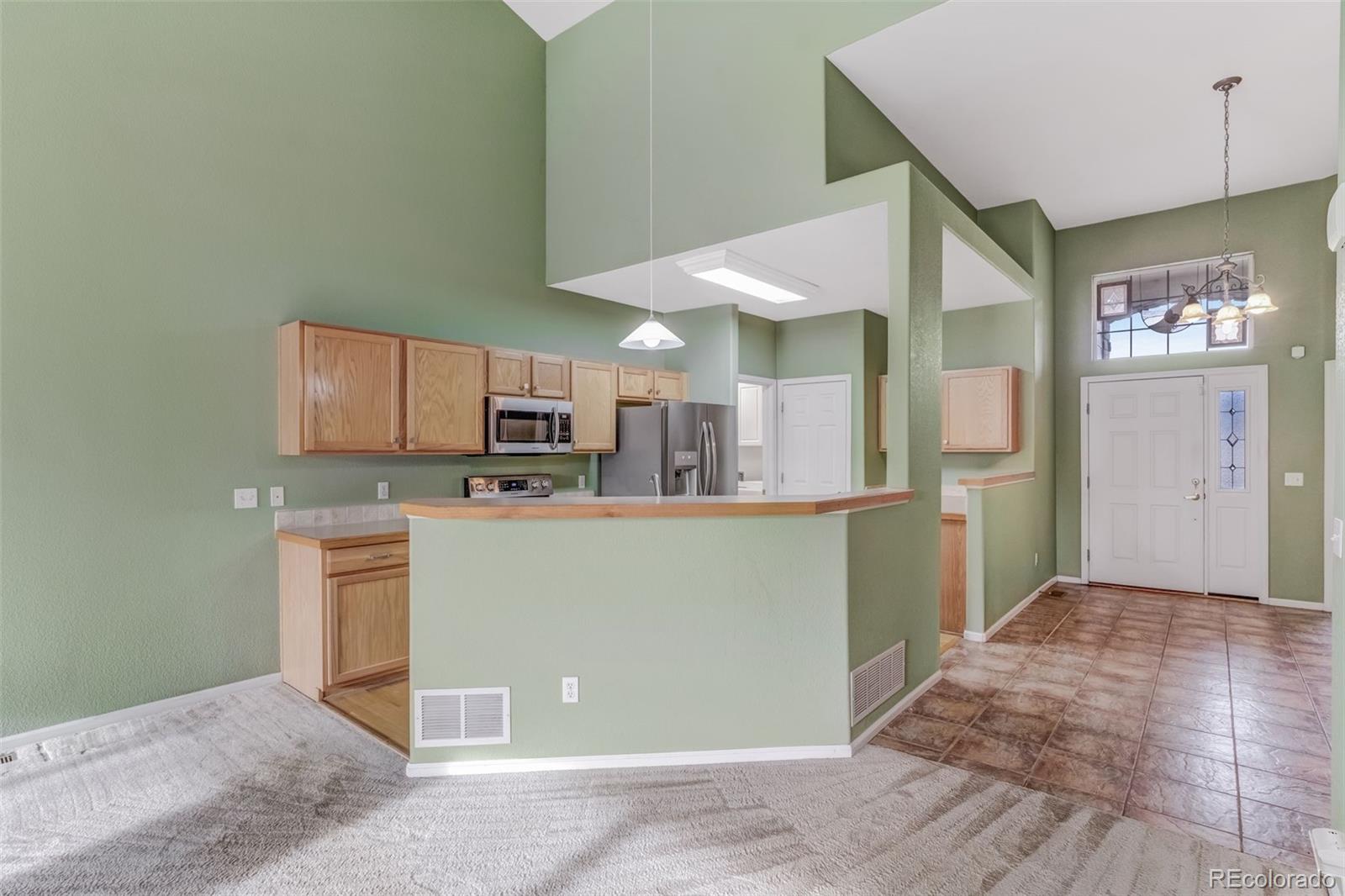 6656 South Reed Way, Unit B Littleton, CO 80123 - Photo 7 of 32 a kitchen with kitchen island granite countertop a refrigerator cabinets and wooden floor