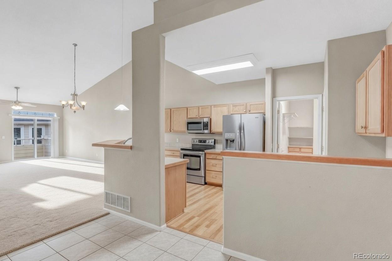 6656 South Reed Way, Unit B Littleton, CO 80123 - Photo 9 of 32 a open kitchen with stainless steel appliances kitchen island granite countertop a refrigerator a stove a sink and a sink
